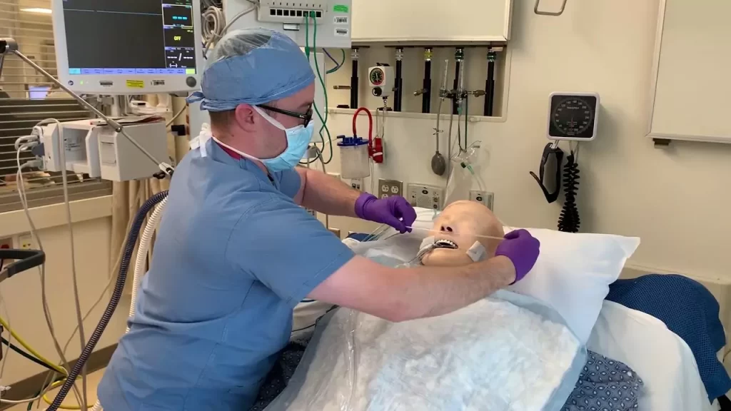 Healthcare professional tending to a patient connected to a ventilator machine in an ICU setting.
